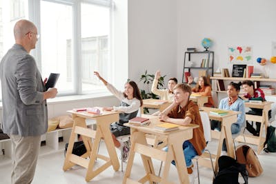 Students raising hands in classroom